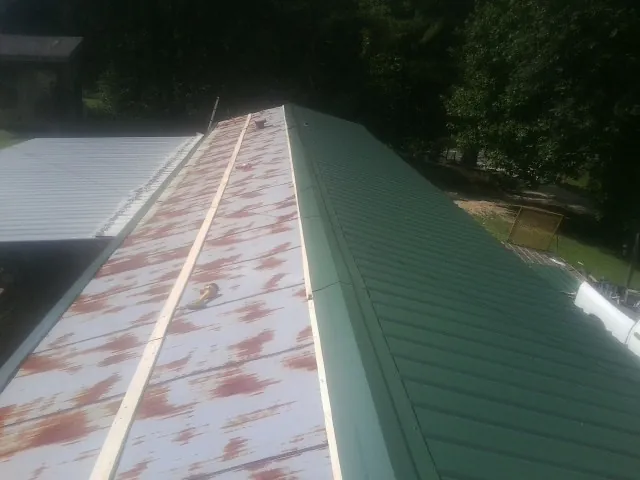 Old rusted panels beside newly installed green metal roofing — Wind Damage Roof Repair by Roofing Brothers in South Yarmouth