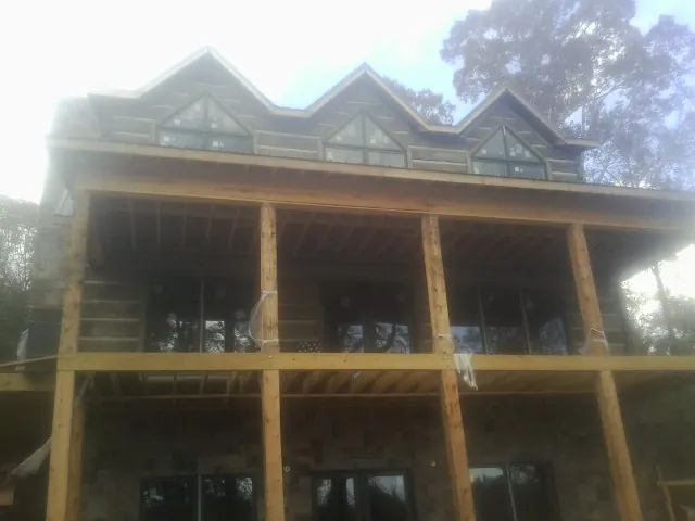 Dormers and porch framing on a large log home under construction — Roof Coating work by our crew in South Yarmouth