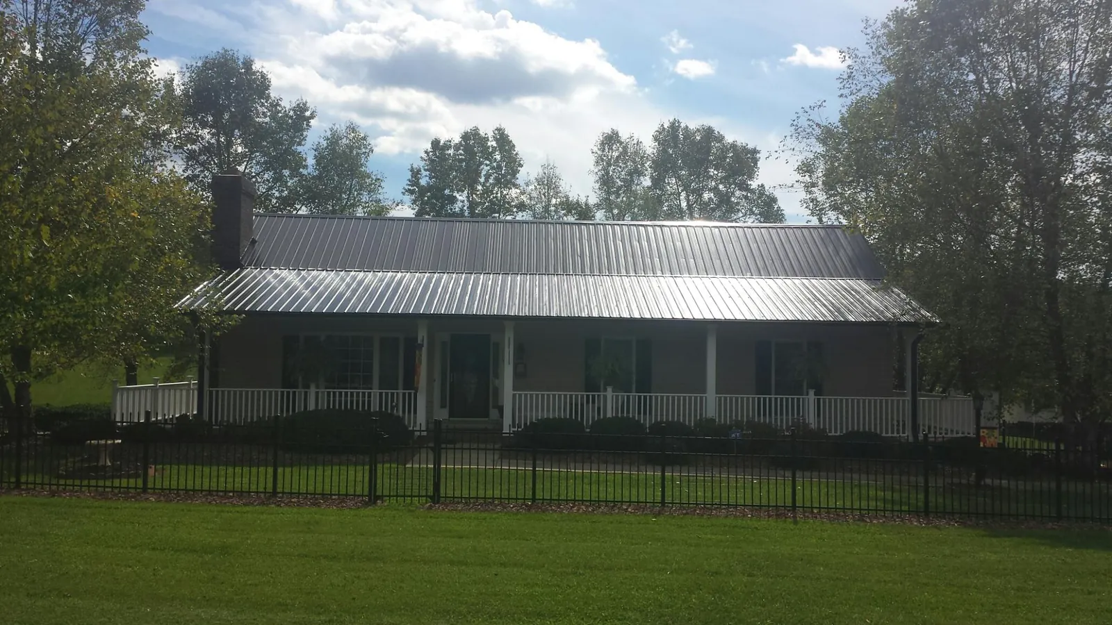 Gray metal roof on a brick ranch with a full width front porch — Gutter Guard Installation work by our crew in South Yarmouth