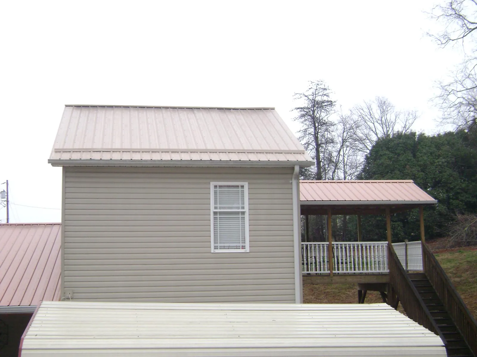 Tan metal roofs on a two story addition and attached porch, from a Roof Replacement job in South Yarmouth