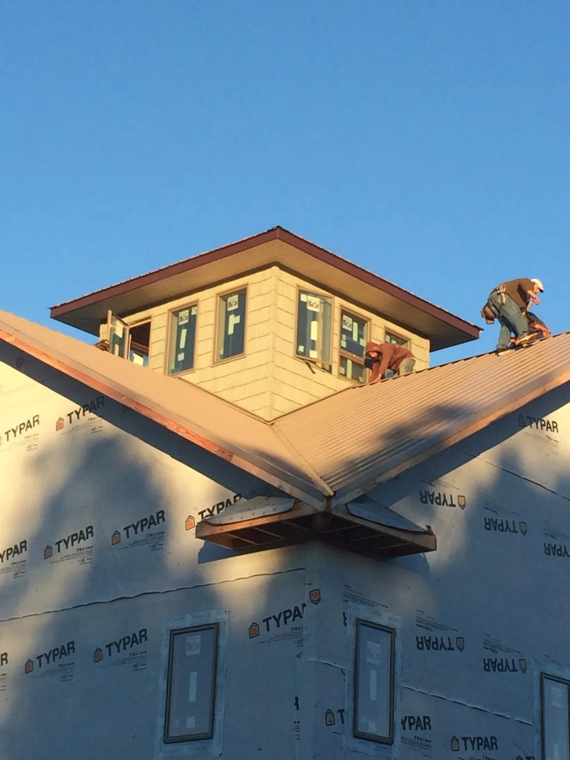 Roofers working around a rooftop cupola on a new metal roof at sunset — Roof Waterproofing in South Yarmouth by Roofing Brothers
